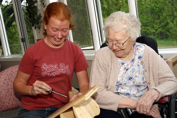 Young female volunteer building wooden project with female resident
