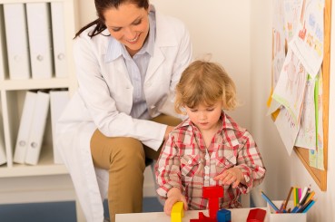 therapist assessing child with building blocks