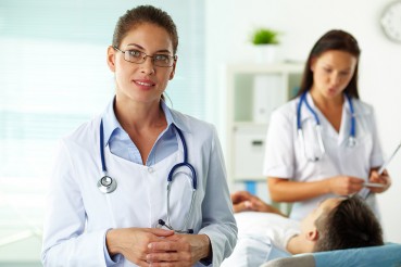 health provider standing by a patient with other health provider
