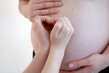 Pregnant stomach with child's hands making a heart shape