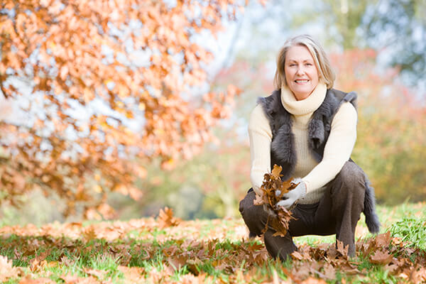 Senior woman collecting autumn leaves on walk